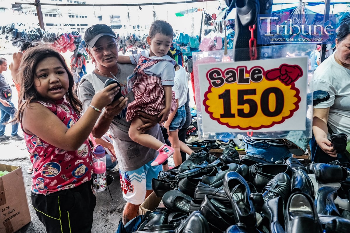 Edwin Ibanez, 55 years old, takes her daughter Precious, 4 years old, to buy new shoes with the help of her older sister Princess Nicole, 7 years old on July 18, 2024. PHOTO BY YUMMIE DINGDING